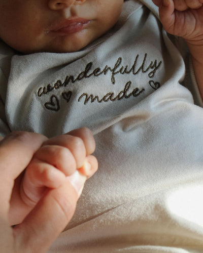 Cute baby smiling in a shirt that says "i am pro-life", brown corduroy pants, and grey striped socks.